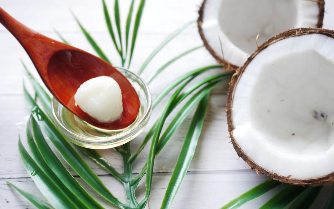 a wooden spoon with a facial scrub next to plans and a coconut to represent organic products